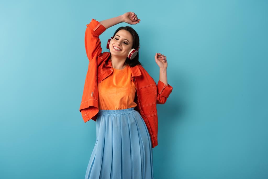 hymyilevä nainen kuulokkeet tanssia ja kuunnella musiikkia sinisellä taustalla
  - Valokuva, kuva