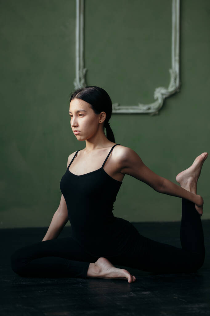 Girl is doing stretching exercise. Yoga class in black sportswear. - Photo, Image