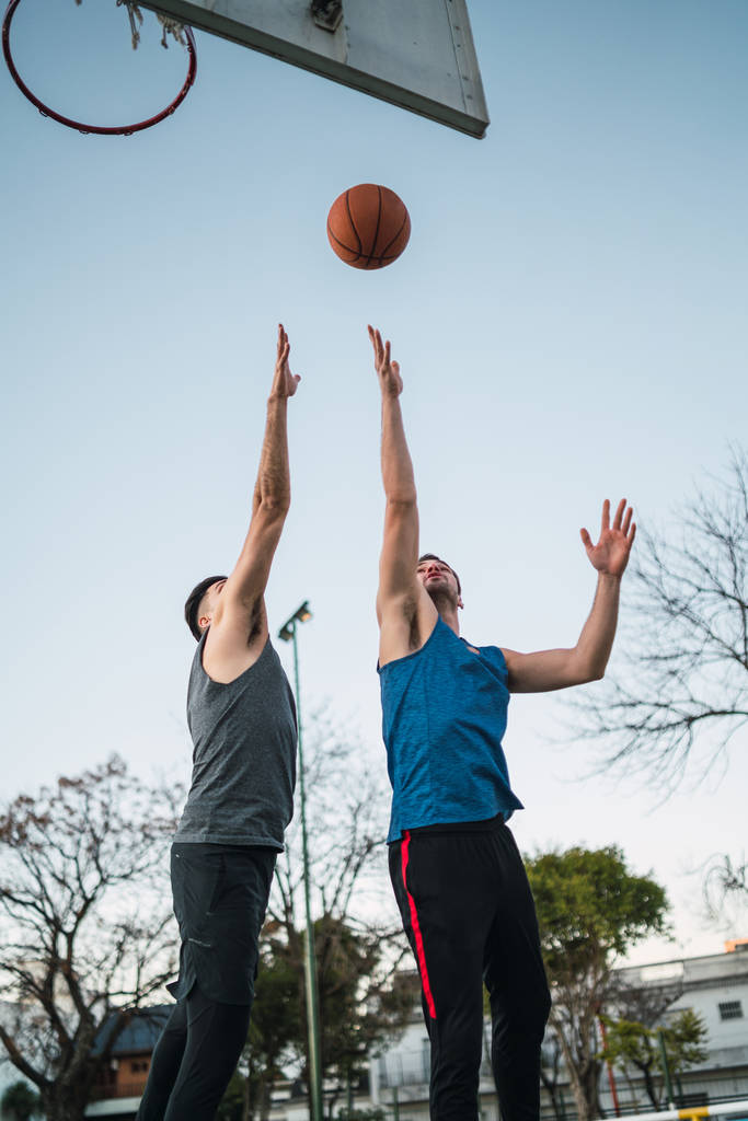 Portret van twee jonge vrienden die basketbal spelen en plezier hebben op het veld. Sportconcept. - Foto, afbeelding