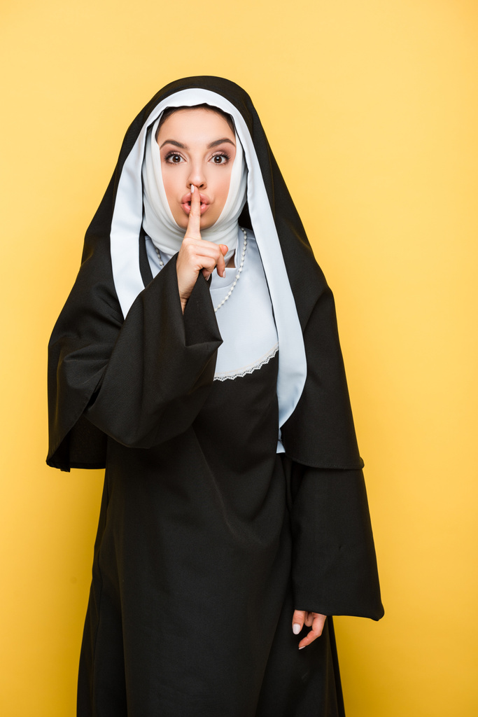 красивая монахиня с символом тишины, на желтом
 - Фото, изображение