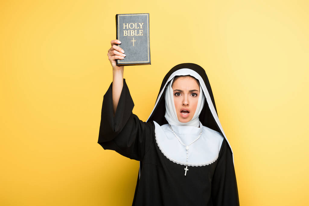 шокована черниця тримає святу Біблію на сірому
 - Фото, зображення