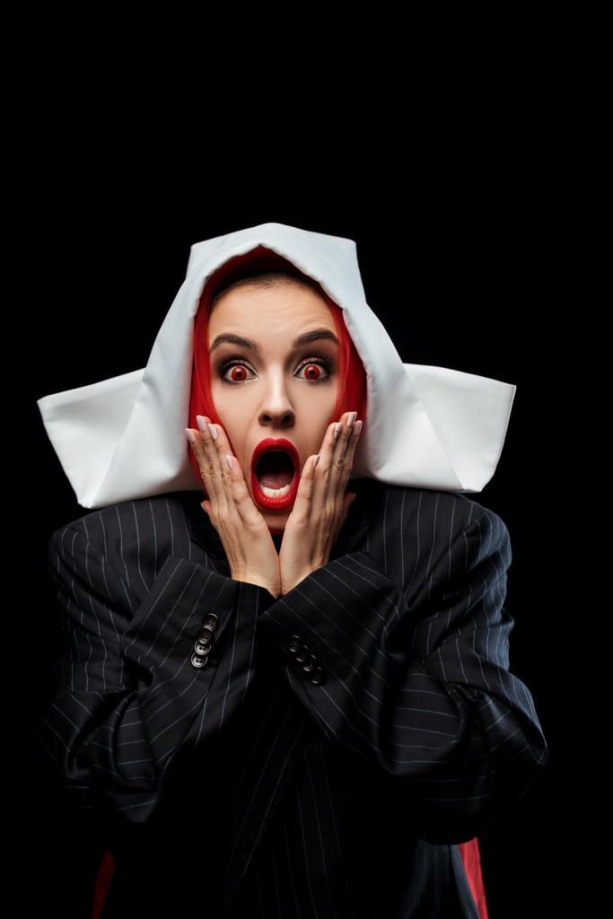 wstrząśnięta demoniczna zakonnica z czerwonymi oczami i otwartymi ustami odizolowana na czarno - Zdjęcie, obraz