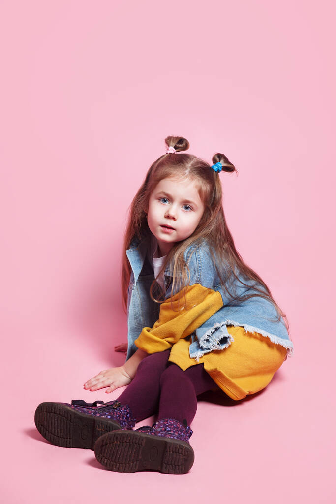 Стильна дівчинка 4-5 років у джинсовому одязі, що позує на рожевому фоні
 - Фото, зображення