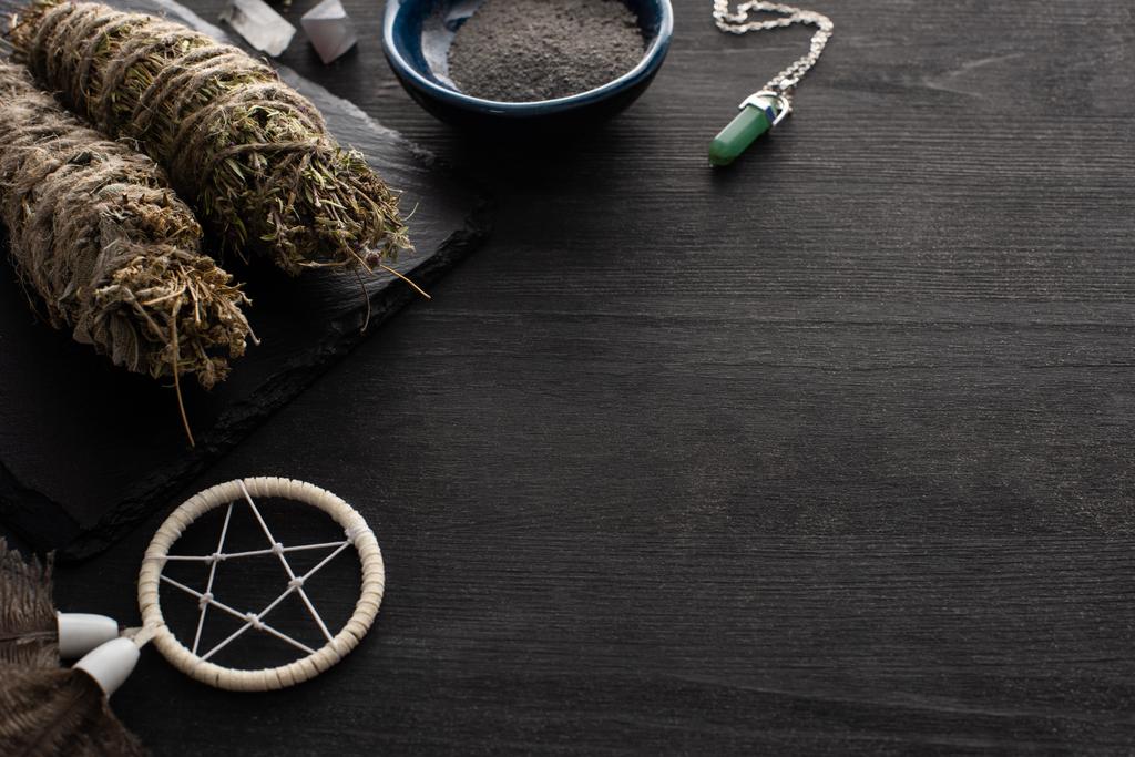 Dreamcatcher avec bâtons de tache, cristal magique et bol de cendres sur fond de bois noir
 - Photo, image