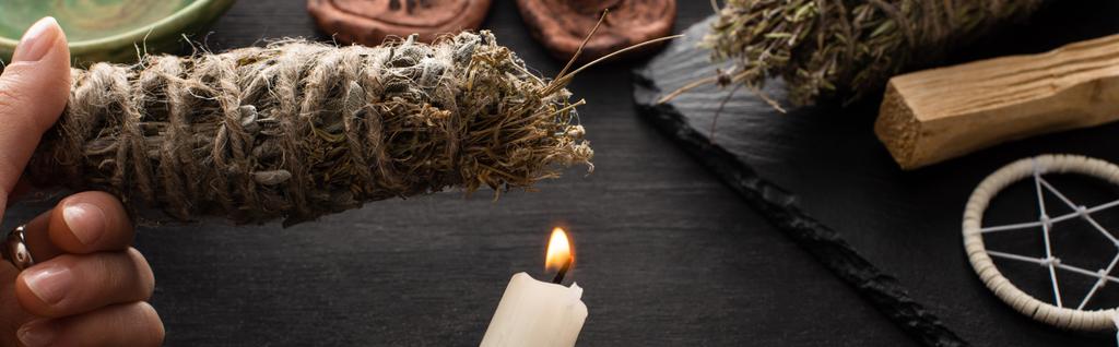 Обрізаний вид шамана, що тримає пляму і свічку біля чаклунства на чорній дерев'яній поверхні, панорамний знімок
  - Фото, зображення