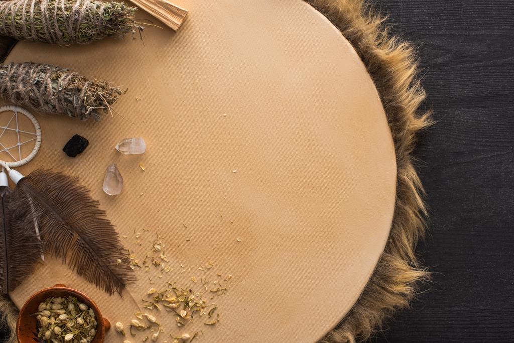 Вид сверху на шаманские грязные палочки, сновидения и волшебные кристаллы на тамбуре на темном деревянном фоне
 - Фото, изображение