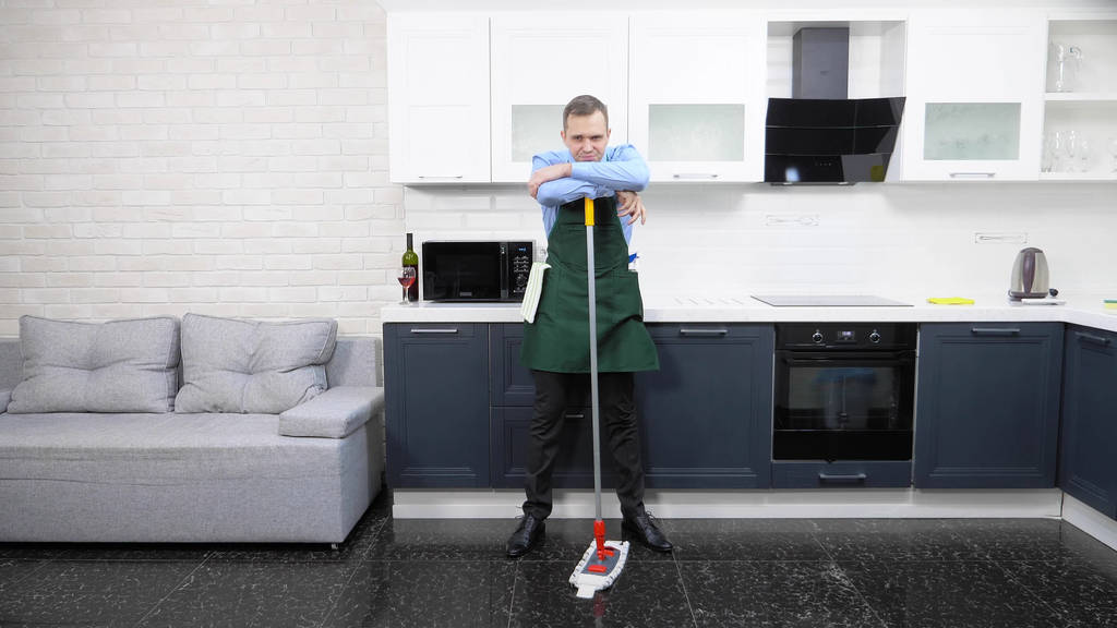  ネクタイのハンサムな男とエプロンはキッチンの床を湿らせ - 写真・画像