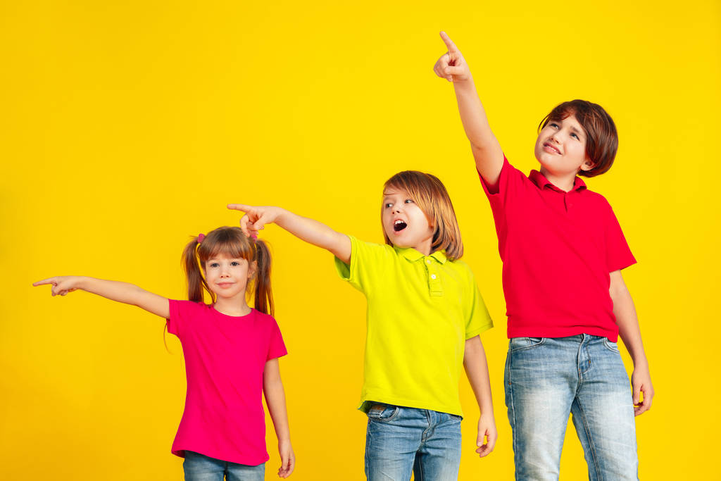 Enfants heureux jouant et s'amusant ensemble sur fond jaune studio
 - Photo, image