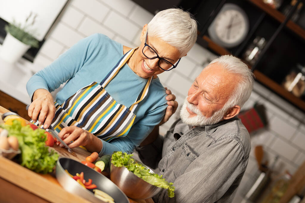Coppia senior cucinare insieme, mettendo un sacco di amore nel loro pasto - Foto, immagini