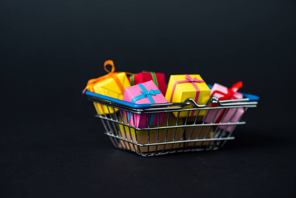 вибірковий фокус барвистих подарункових коробок у кошику для покупок на чорному
  - Фото, зображення