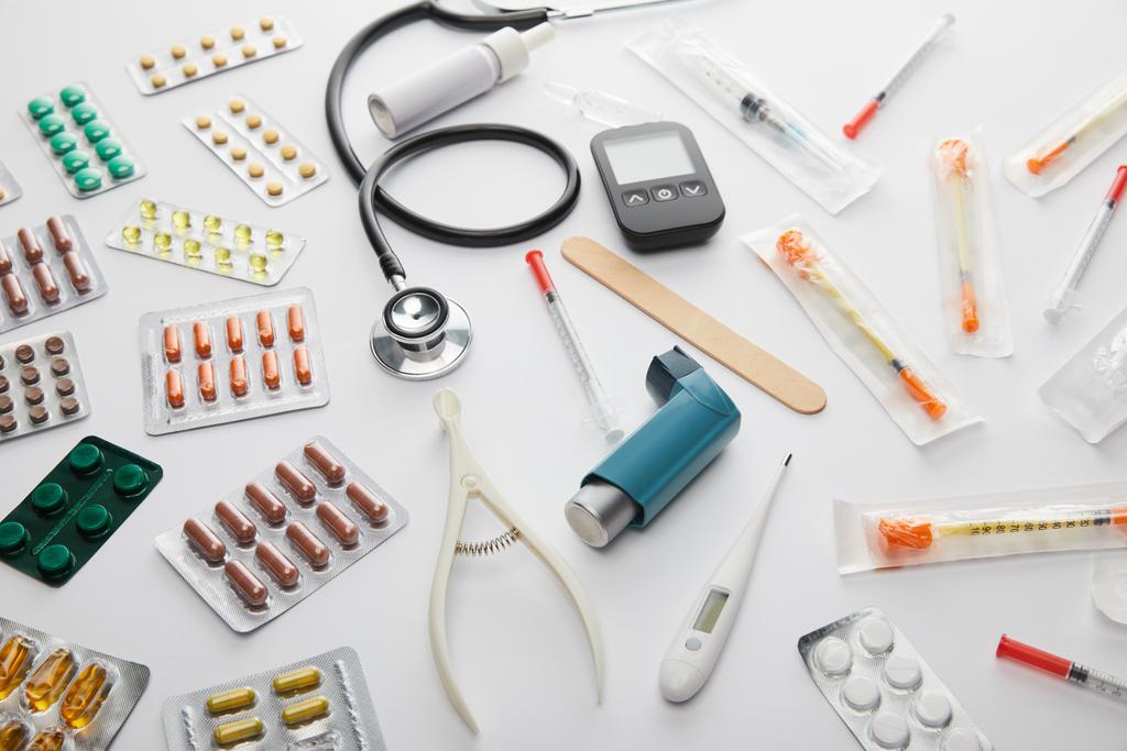 Hochwinkelaufnahme von Medikamenten, Stethoskop, Thermometer und medizinischen Objekten auf weiß - Foto, Bild