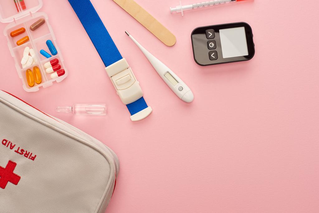 Vista superior do kit de primeiros socorros, pílulas e objetos médicos em rosa
 - Foto, Imagem