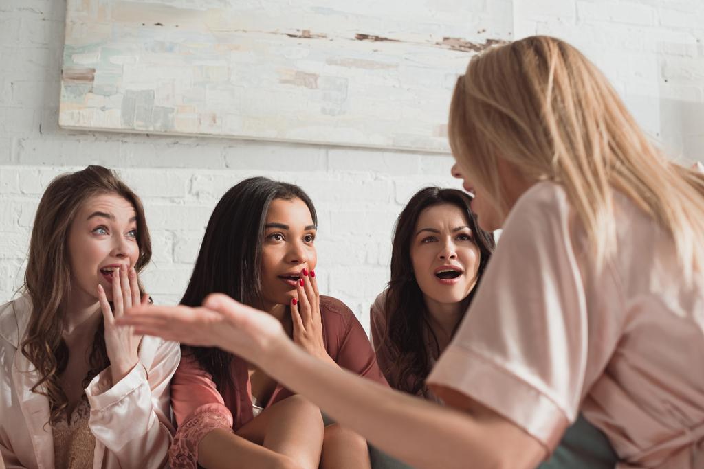 Foco seletivo de mulheres multiculturais chocadas conversando na despedida de solteira
 - Foto, Imagem