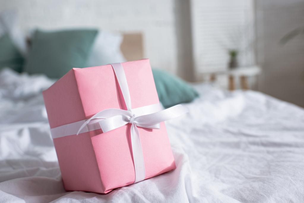 Valikoiva painopiste vaaleanpunainen lahjapakkaus sängyssä huoneessa
 - Valokuva, kuva