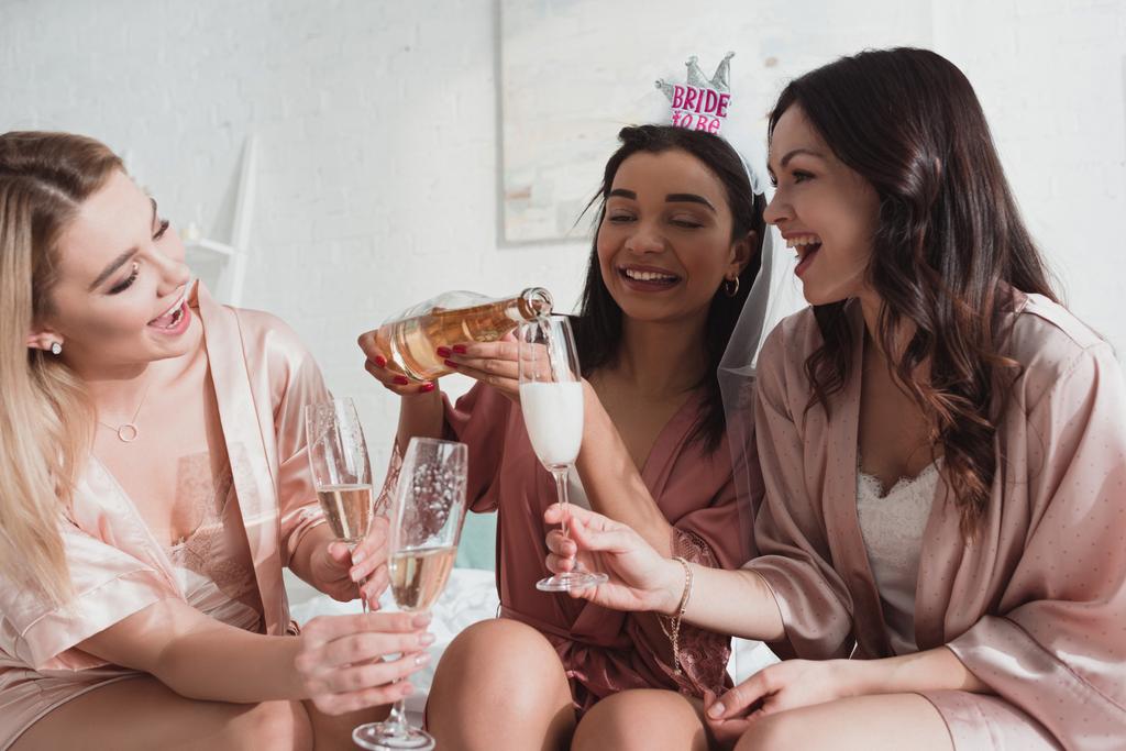 アフリカ系アメリカ人の花嫁がシャンパンをグラスに注ぐ友人とともにbacheroreetteパーティー - 写真・画像