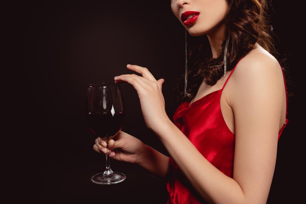 Ausgeschnittene Ansicht einer eleganten jungen Frau mit einem Glas Rotwein isoliert auf Schwarz - Foto, Bild