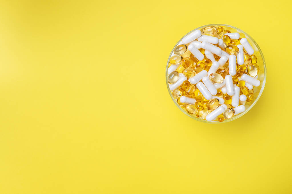 Lääkkeet vitamiinit tabletit ja pillerit lautasella. Keltainen tausta. Kopio tilasta
 - Valokuva, kuva
