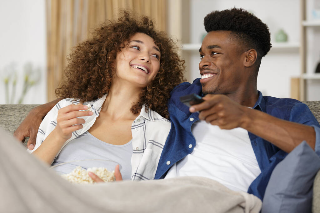 щаслива багаторасова пара з попкорном дивитися телевізор
 - Фото, зображення