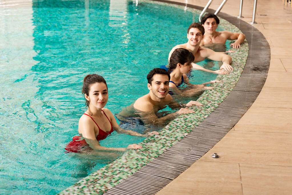 Sonriendo a la gente mirando a la cámara mientras entrenan en la piscina
 - Foto, Imagen