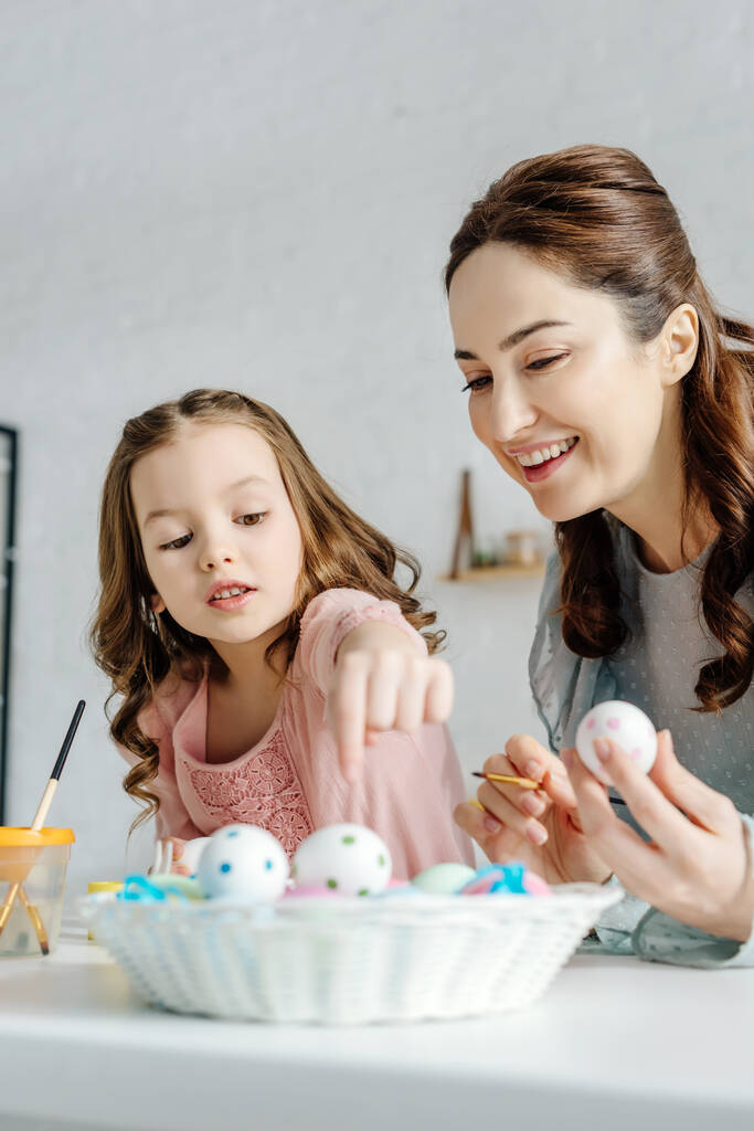selektivní zaměření šťastné matky a dítěte v blízkosti velikonočních vajec  - Fotografie, Obrázek