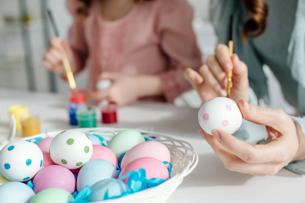 enfoque selectivo de huevos de Pascua pintados cerca de la madre y la hija
  - Foto, Imagen