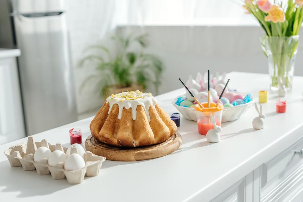 pastel de Pascua dulce cerca de huevos de pollo pintados, tulipanes y conejos decorativos
  - Foto, imagen