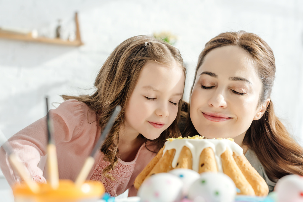 επιλεκτική εστίαση της ευτυχούς μητέρας και της κόρης μυρίζοντας κέικ Πάσχα  - Φωτογραφία, εικόνα