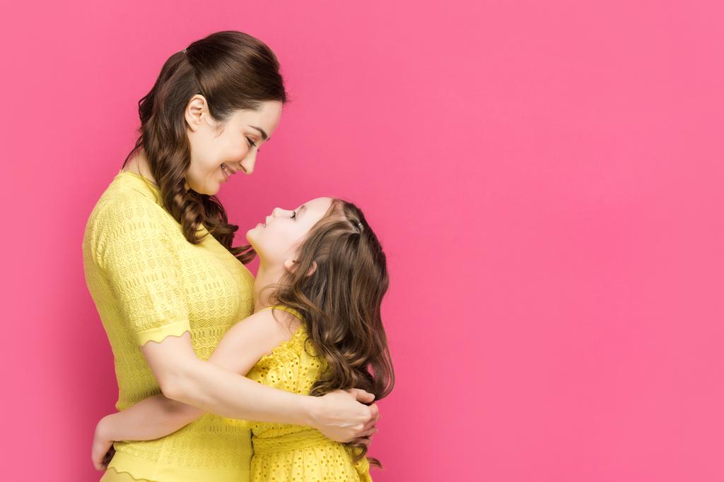陽気な母親と娘のプロフィールピンクで隔離された抱擁  - 写真・画像
