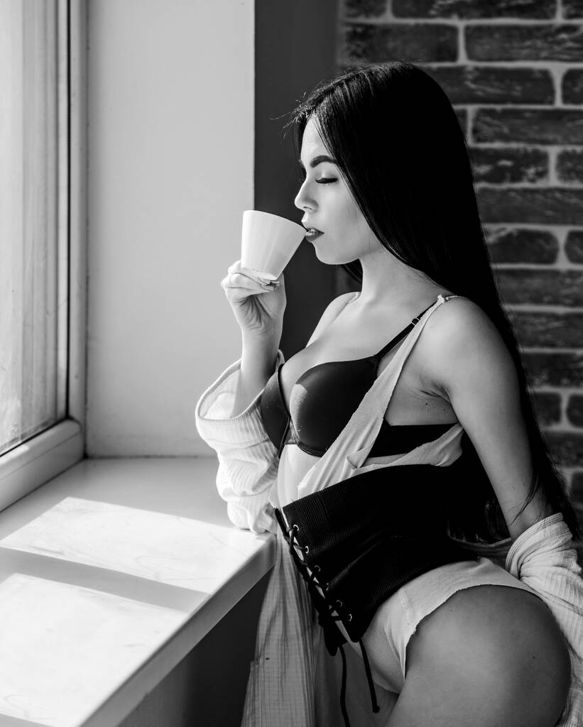 Tökéletes kávé idő. De előbb a kávé. Nyugodtság és béke. Egy korty tejszínes cappuccino. Reggeli rituálé. A tökéletes lány az ablakpárkány közelében issza a kávét. Nő fehérnemű pihentető otthon - Fotó, kép