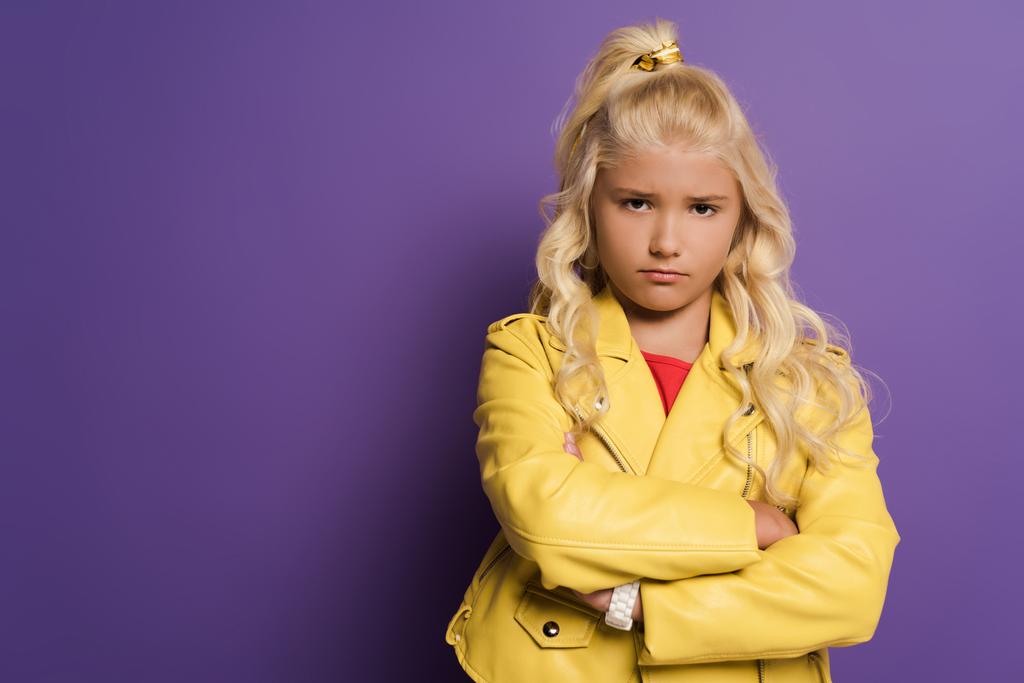 offended kid with crossed arms looking at camera on purple background  - Photo, Image