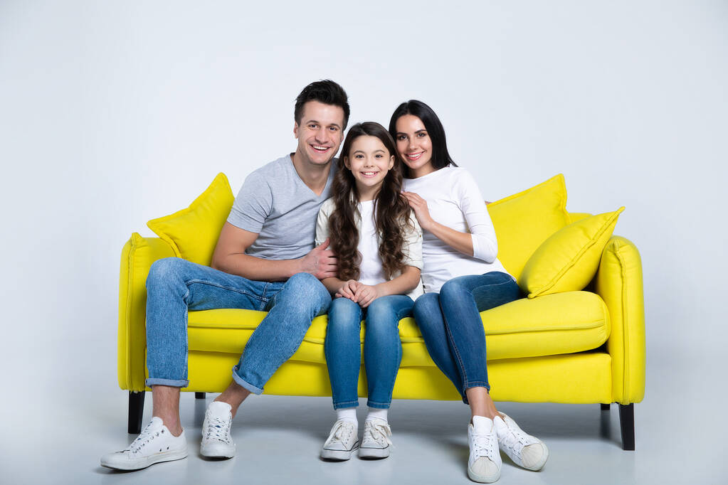 portré boldog fiatal család ül sárga kanapén - Fotó, kép