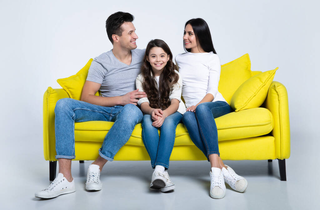Porträt einer glücklichen jungen Familie auf gelbem Sofa - Foto, Bild