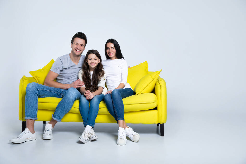 πορτρέτο της χαρούμενης νεαρής οικογένειας κάθεται σε κίτρινο καναπέ - Φωτογραφία, εικόνα
