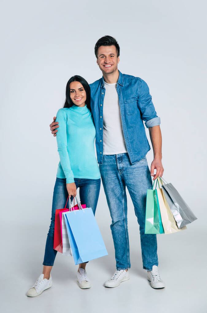 young couple holding shopping bags and smiling at camera isolated on white - Photo, Image