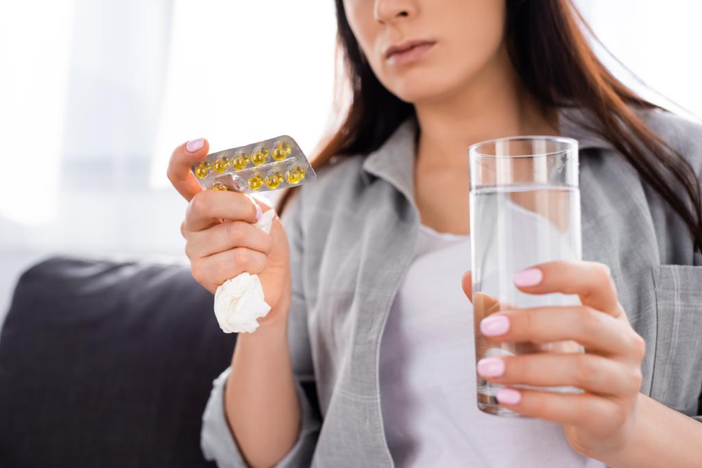 kivágott kilátás nő gazdaság buborékcsomagolás tabletták és pohár víz  - Fotó, kép