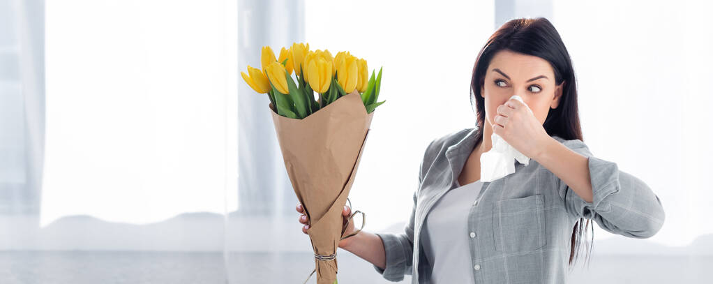 панорамный снимок чихающей женщины с аллергией на пыльцу, смотрящей на тюльпаны
  - Фото, изображение