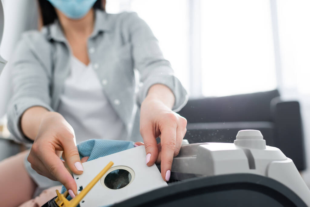 cropped view of allergic woman in medical mask holding dust bag near vacuum cleaner - Photo, Image