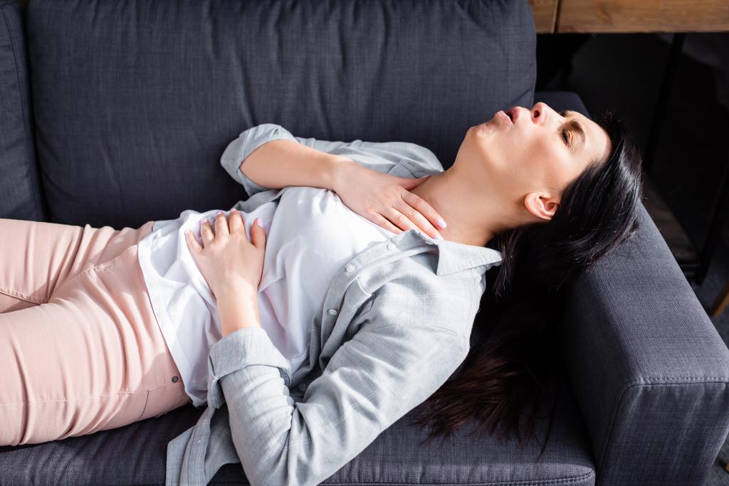 астматична жінка кашляє, лежачи на дивані
  - Фото, зображення