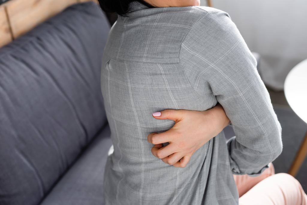 vista recortada de la mujer con alergia rascarse la espalda mientras está sentado en el sofá
  - Foto, imagen