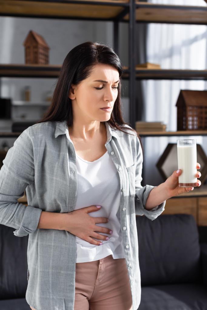 traurige Frau mit Laktoseintoleranz hält Glas Milch in der Hand  - Foto, Bild