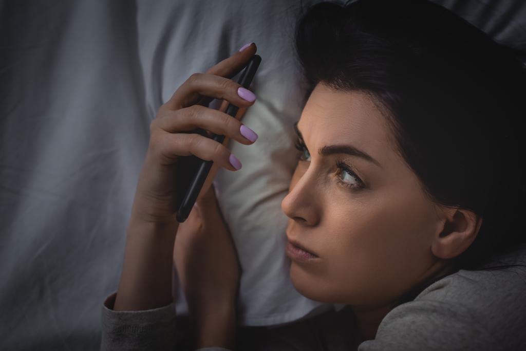 κορυφαία άποψη της ξύπνιας γυναίκας με αϋπνία χρησιμοποιώντας smartphone  - Φωτογραφία, εικόνα