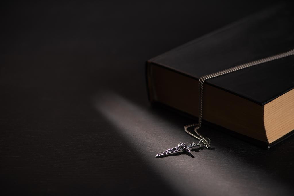 Biblia santa con cruz sobre fondo negro oscuro con velas encendidas
 - Foto, imagen