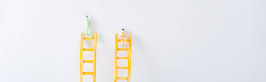 Panoramaaufnahme von zwei Personen auf Leitern auf weißem Hintergrund, Konzept der Gleichberechtigung  - Foto, Bild