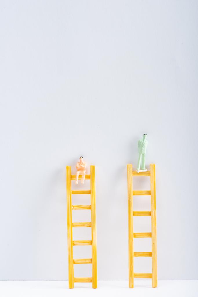Dos figuras de personas en escaleras sobre superficie blanca sobre fondo gris con espacio de copia, concepto de derechos de igualdad
  - Foto, imagen