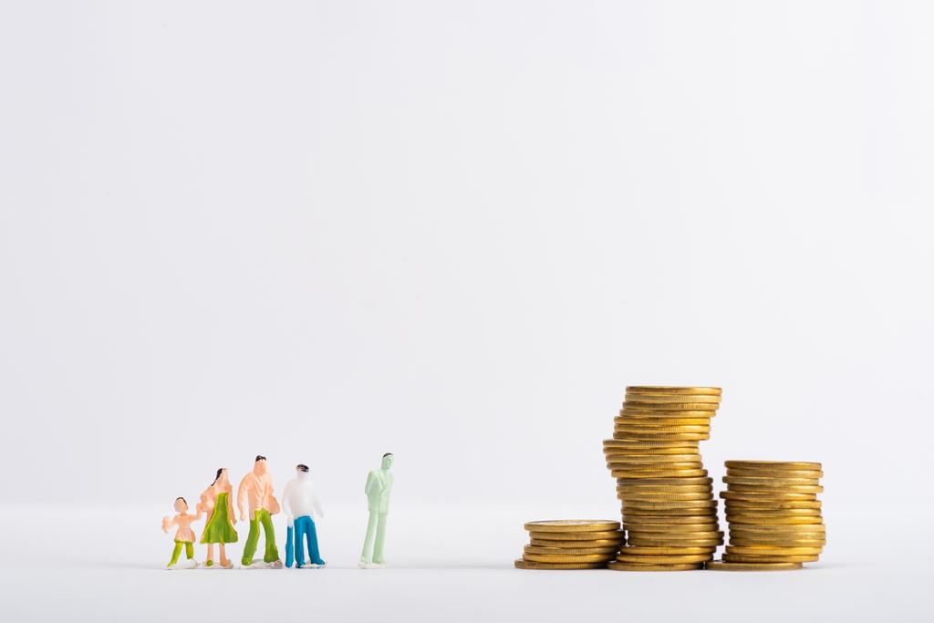 Cifras de gente de juguete cerca de estafas apiladas en superficie blanca aislada en gris, concepto de igualdad financiera
 - Foto, Imagen