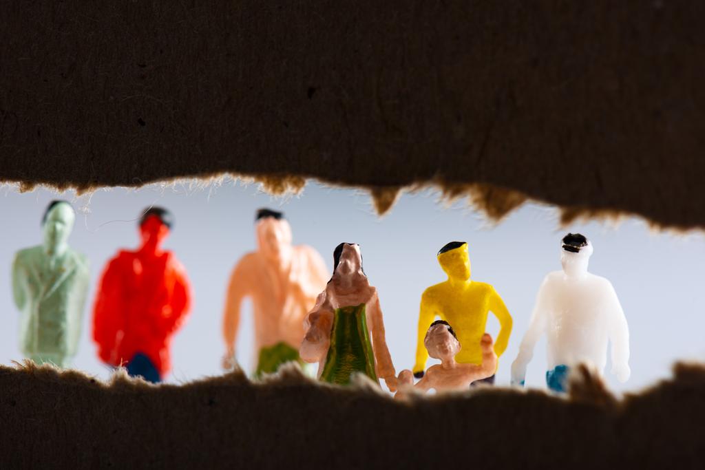 Foco seletivo de papelão com buraco e figuras de pessoas isoladas em cinza
 - Foto, Imagem