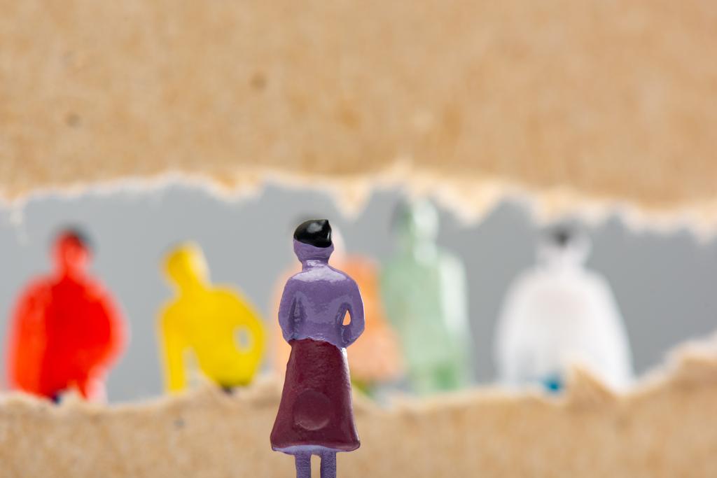 Selective focus of toy near hole in cardboard with people figures isolated on grey, concept of social rights  - Photo, Image