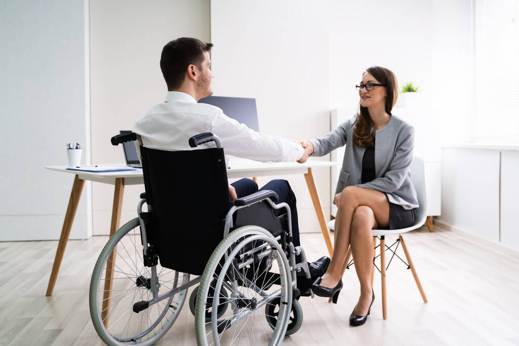İş kadını ofiste onun meslektaşı ile el sıkışan tekerlekli sandalyede - Fotoğraf, Görsel