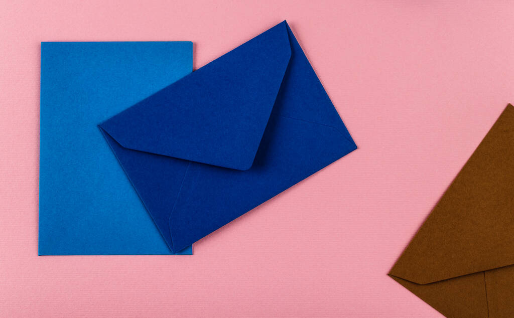 Kleurrijke enveloppen op een roze achtergrond. Postenveloppen op tafel. - Foto, afbeelding