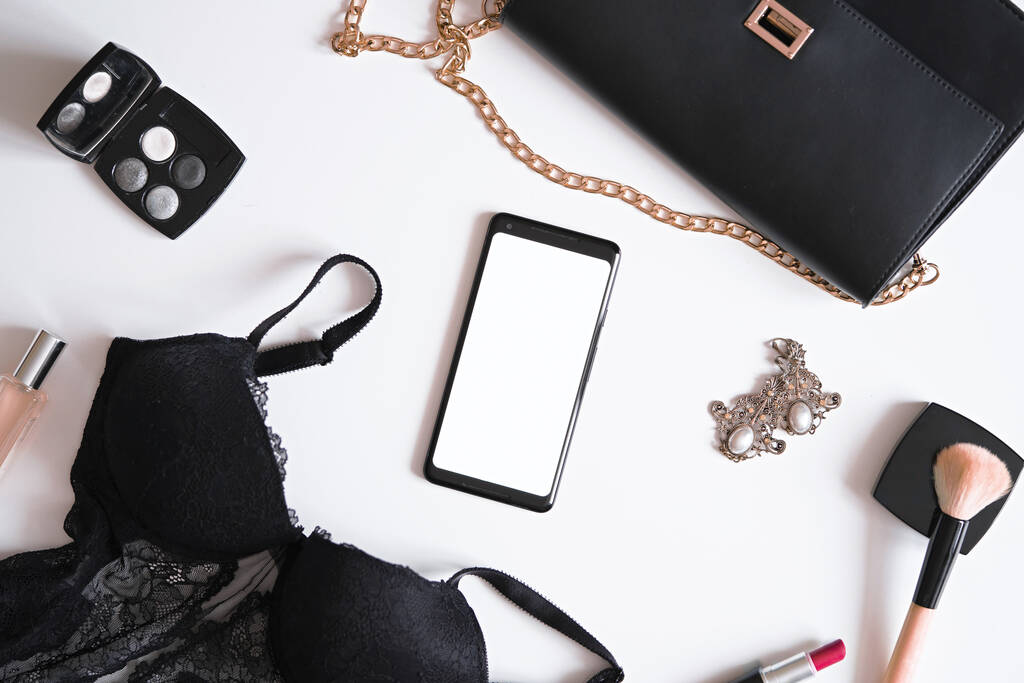Flat Lay of Mobile Phone With Blank Screen Near Lingerie, Earrings, Cosmetics, Perfume, Make up Brush, Clutch Bag. Getting ready For Party - Fotoğraf, Görsel